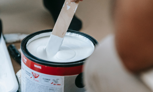Stirring white paint with a paint stick